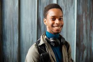 Student smiling with headphones in the Noel Fine Arts Center.