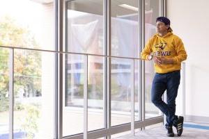 一名学生在德雷福斯大学中心望向窗外，穿着一件金色的威斯康星大学史蒂文斯角分校运动衫.