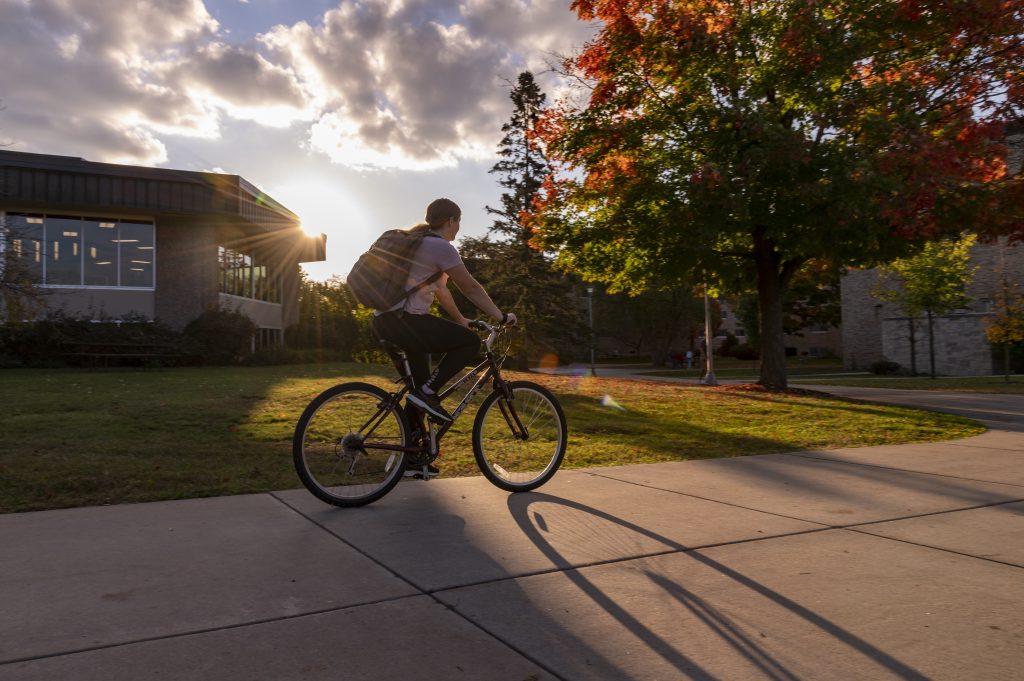 日落时分，学生在德博特餐饮中心旁的人行道上骑自行车.